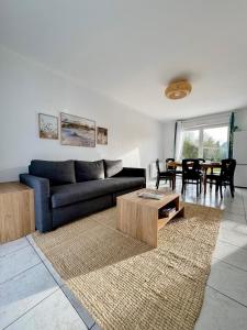 uma sala de estar com um sofá azul e uma mesa em Charmante maison familiale em Ouistreham