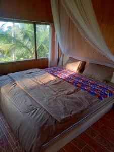 uma cama num quarto com uma janela em Coconut Homestay Tetebatu em Tetebatu