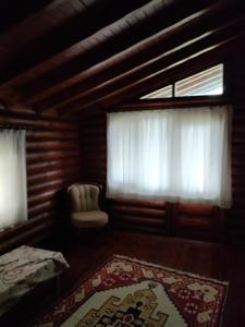 1 dormitorio con ventana, silla y alfombra en Chalet's lake_Bolu Abant _log house, en Piroğlu