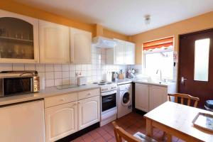 a kitchen with white cabinets and a table and a sink at Garden Cottage Helensburgh in Helensburgh