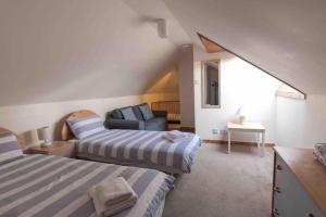 a attic bedroom with two beds and a couch at Garden Cottage Helensburgh in Helensburgh