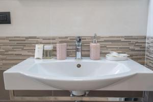 een witte wastafel in een badkamer met een spiegel bij Ferienwohnung für 4 Personen ca 58 qm in Alghero, Sardinien Sassarese in Alghero
