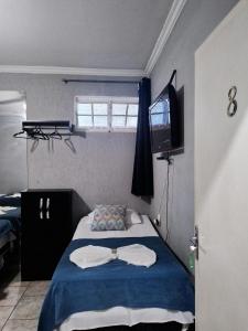 1 dormitorio con 1 cama con sábanas azules y TV en Pousada uberaba, en Uberaba