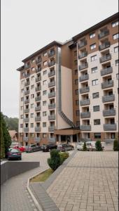 un grand immeuble avec des voitures garées dans un parking dans l'établissement Apartman MOMENTUM, à Zlatibor