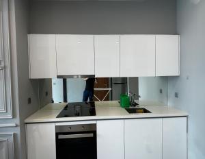 una cocina con armarios blancos y una persona en el fondo en High Floor Lux Apartment Across KLCC, en Kuala Lumpur 3 fotos más