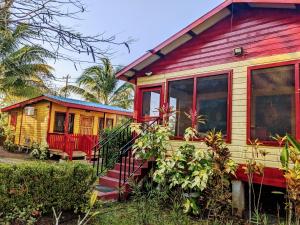 a red and yellow tiny house next to a building at Garden Cottage in San Ignacio