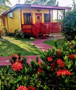 a yellow and red house with flowers in front of it at Garden Cottage in San Ignacio