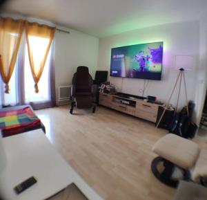 ein Wohnzimmer mit einem TV, einem Sofa und einem Stuhl in der Unterkunft Cosy appart T4 90m~ Proche Paris - 5 min du RER C in Arpajon
