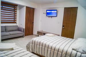 Habitación de hotel con 2 camas, sofá y TV en Depto 5 Centro Expositor, en Puebla