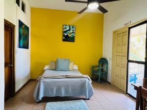 a bedroom with a bed with a yellow wall at Hotel Del Rio in San Pedro