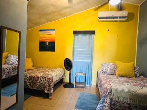 a room with two beds and a yellow wall at Hotel Del Rio in San Pedro