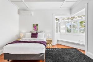 een witte slaapkamer met een bed en een raam bij Spacious Kingsland 4BR Home in Auckland