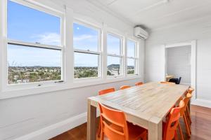 comedor con mesa de madera y sillas naranjas en Spacious Kingsland 4BR Home, en Auckland