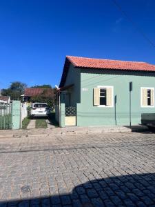 a green house with a car parked in front of it at Casinha Verde in Passa Quatro
