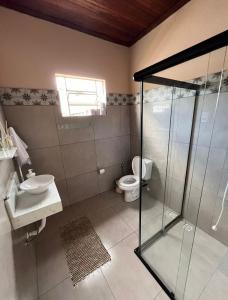 a bathroom with a glass shower and a toilet at Casinha Verde in Passa Quatro +26 photos