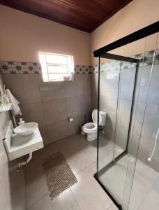 a bathroom with a glass shower and a toilet at Casinha Verde in Passa Quatro