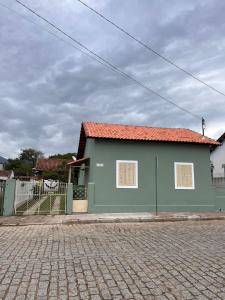 a green building with a red roof on a street at Casinha Verde in Passa Quatro