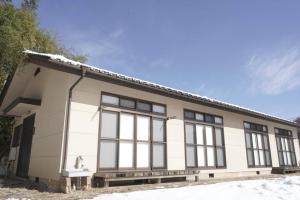 un edificio bianco con ampie finestre nella neve di 布施温泉ステイ　イースト a Saku