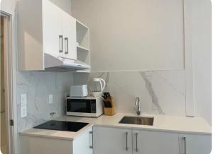 a white kitchen with a sink and a microwave at Newly renovated home in Auckland city in Auckland