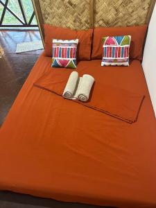uma cama com duas almofadas e duas toalhas em HIRAYA Camp Site - FREE use of SCOOTER for NIPA HUTS em El Nido