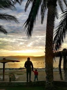 Un hombre y un niño caminando por la playa en Acogedora Casa en Condominio Oasis, en Paracas