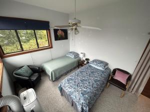a bedroom with two beds and a chair and a window at Charming Hidden Gem- Ocean View and Marina in Campbell River