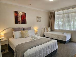 a hotel room with two beds and a window at Alstonville Settlers Motel in Alstonville