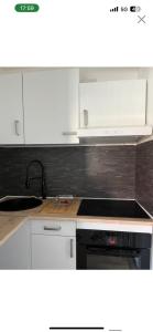a kitchen with white cabinets and a stove top oven at Studio 30 min de Paris in Argenteuil
