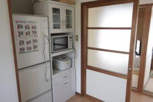 a kitchen with a refrigerator and a microwave at 布施温泉ステイ　ウエスト in Saku