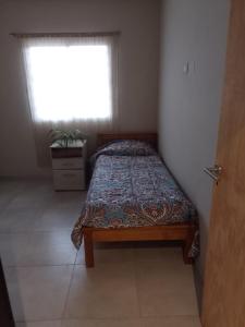 un letto in una camera con finestra e copriletto di Apart Los Laureles a Villa Regina