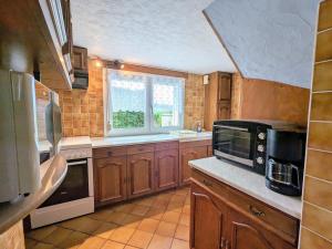 Laveline-du-HouxGîte rustique à Laveline-du-Houx, proche forêt - FR-1-589-141的厨房配有木制橱柜、微波炉和窗户。