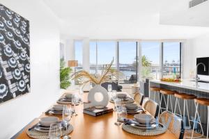 a dining room with a table with plates and glasses at Beach Street Luxury 3 Bed with Beach & Bay Views in Melbourne