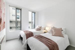 two beds in a room with two windows at Beach Street Luxury 3 Bed with Beach & Bay Views in Melbourne