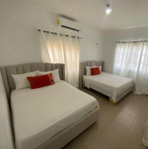 two beds in a bedroom with white walls and red pillows at La Castillada House in Santa Cruz de Barahona