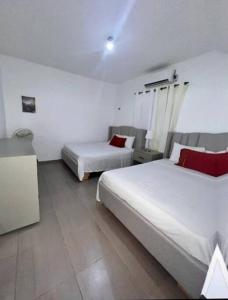 two beds in a hotel room with red pillows at La Castillada House in Santa Cruz de Barahona