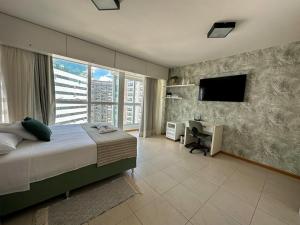 a bedroom with a bed and a desk and a television at Flat Saint Moritz Brasília Hotel in Brasilia