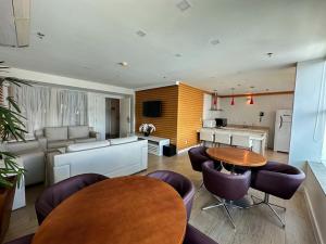 a living room with tables and chairs and a kitchen at Flat Saint Moritz Brasília Hotel in Brasília
