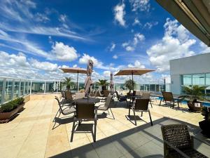 eine Terrasse mit Tischen, Stühlen und Sonnenschirmen auf einem Gebäude in der Unterkunft Flat Saint Moritz Brasília Hotel in Brasilia