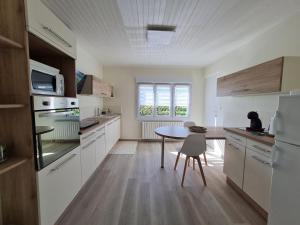 a kitchen with white cabinets and a table in it at Gîte tout confort au bord de la Meuse avec jardin et activités familiales à proximité - FR-1-585-82 in Vilosnes-sur-Meuse