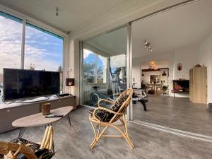 a living room with a tv and a table and chairs at Maison spacieuse avec fitness, massage sur demande et jardin privatif, proche Nantes et Pornic - FR-1-306-1231 in Saint-Philbert-de-Grand-Lieu