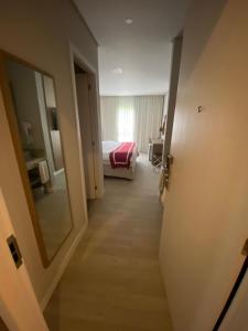 - un couloir d'une chambre d'hôtel avec un lit et un miroir dans l'établissement Flat Incrível - Livyd Angra dos Reis - Hotel do Bosque 3p, à Angra dos Reis