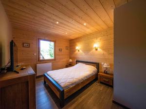 ein Schlafzimmer mit einem Bett in einer Holzhütte in der Unterkunft Chalet familial confortable avec spa, proche Gérardmer et station de ski, idéal été et hiver. - FR-1-589-469 in Ban-sur-Meurthe-Clefcy