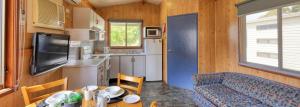 eine kleine Küche mit einem Tisch und einer Couch in einem Wohnwagen in der Unterkunft Highlander Van Village in Armidale