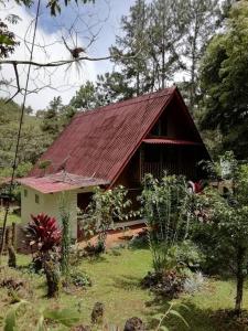 una pequeña casa con techo rojo en un campo en Mountain Chalet, en Los Altos de Cerro Azul