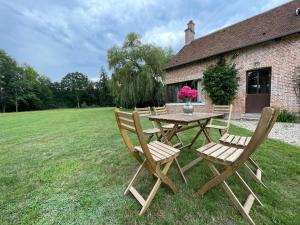 un tavolo in legno con sedie di fronte a una casa di Maison de Charme en Sologne avec Étang Privé, Grand Parc et Cheminée - FR-1-586-37 a Sainte-Montaine