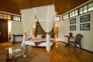 a bedroom with a canopy bed with a glass table at Mandala Spa & Resort Villas in Boracay