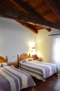 two beds in a room with wooden ceilings at Hostal de Montaña la Casa Grande in Nogueruelas