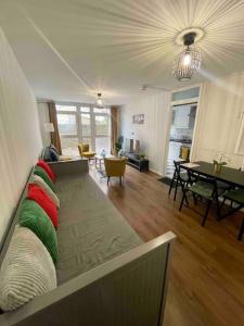 een woonkamer met een bank met rode en groene kussens bij Lovely 2-bed 20 mins to central London in Londen