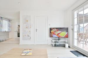 sala de estar blanca con TV de pantalla plana en Haus Strandidyll Haus1, en Timmendorfer Strand