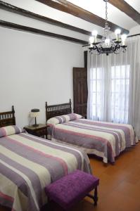 a bedroom with three beds and a chandelier at Hostal de Montaña la Casa Grande in Nogueruelas